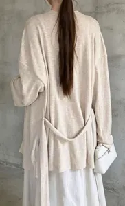 Dettaglio posteriore del cardigan beige ampio con cintura e trama in maglia.