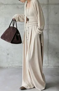 Modella in completo 3 pezzi beige con cardigan e pantaloni larghi e borsa scamosciata
