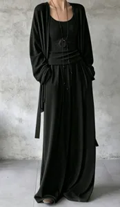 Dettaglio di un set tre pezzi nero minimalista con cardigan lungo e pantaloni a gamba larga