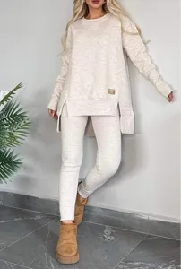 Detail shot of beige split hem long sleeve top and pants set worn in casual indoor setting.