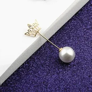 Detailansicht einer eleganten goldenen Kronenbrosche mit einem polierten weißen Perlenakzent