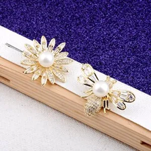 Detailansicht von goldenen Bienen- und Blumenbroschen mit Perlen und Kristallen