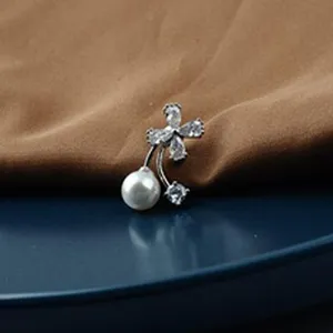 Close-up detail of silver-tone brooch featuring sparkling zircons and a white pearl