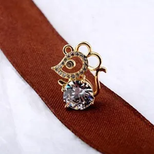 Detaillierte Makroansicht einer goldenen Maus-Brosche mit facettiertem Kristall und Strass