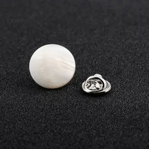 Nahaufnahme des weißen Perlmutt-Sicherheitsknopfs mit silbernem Schmetterlingsverschluss.