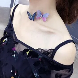 Primer plano de una modelo con una gargantilla con doble colgante de mariposa en azul y púrpura.