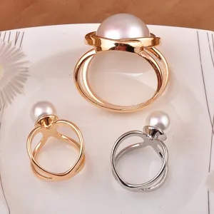 Close-up van elegante gouden en zilveren sjaalringen met parels op een wit bord