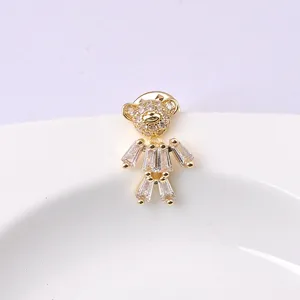 Detailed macro view of a cute gold-plated teddy bear brooch with sparkling crystals.