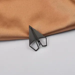 Primo piano di una spilla minimalista a forma di aereo di carta in acciaio nero.