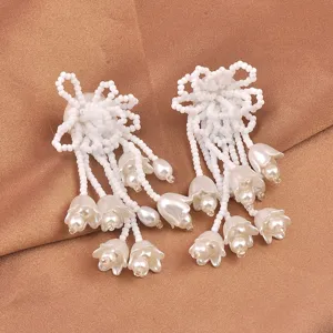 Detailaufnahme von zarten weißen Maiglöckchen-Ohrringen mit Perlen und Perlen-Quasten