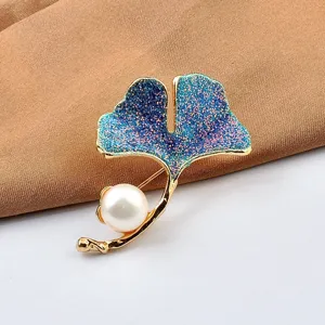 Detailaufnahme einer eleganten Ginkgoblatt-Brosche mit blauem Glitzer und weißer Perle