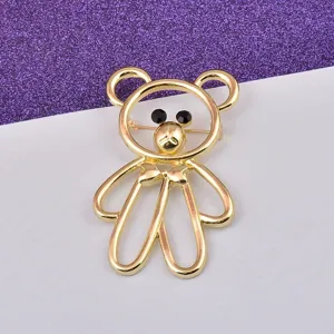 Close-up of a gold-toned hollow bear brooch with black crystal eyes and bow