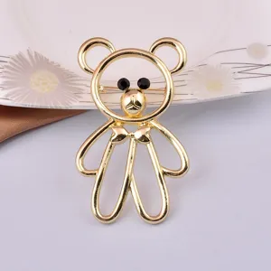 Detailed front view of a cute gold bear brooch with black stone eyes and a bow tie.