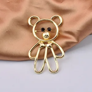 Close-up detail of a charming gold hollow bear brooch with tiny black eyes on satin