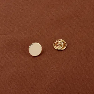 Detailed close-up of a minimalist round gold metal brooch pin with secure butterfly clutch