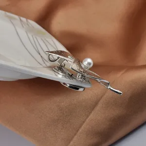Close-up of silver magnet brooch converter with pearl detail on a silk background