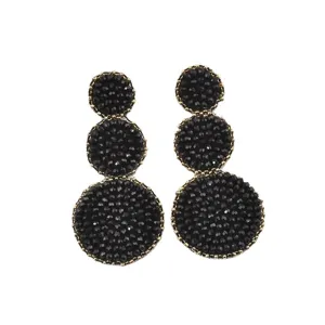 Dettaglio orecchini a mano con perle di cristallo nero e design a tre cerchi