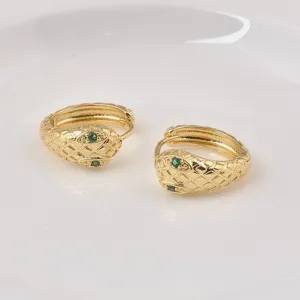 Nahaufnahme goldener Vintage-Schlangenohrringe mit smaragdgrünen Schmucksteinen.