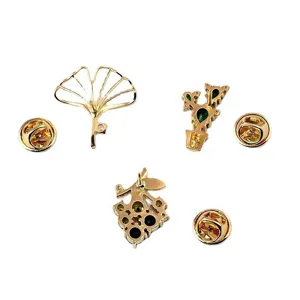 Detailed back view of three plant-themed gold brooches showing pin buckle closures.