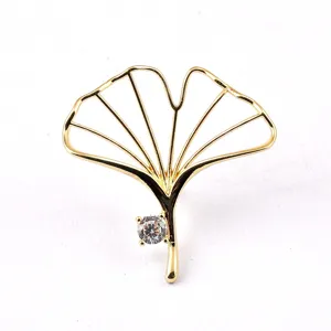 Detailed view of an elegant gold hollow ginkgo leaf brooch featuring a clear crystal accent