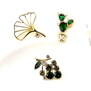 Elegant plant-themed gold brooches featuring ginkgo leaf, cactus, and grape designs.