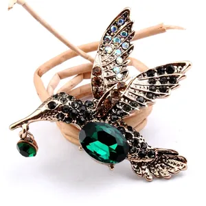 Nahaufnahme einer Vintage-Kolibri-Brosche mit grünen Kristallen und schwarzen Strasssteinen