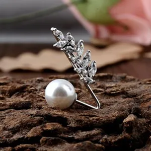 Detaillierte Makroansicht einer eleganten Perlenbrosche mit Kristallblatt auf Naturrinde