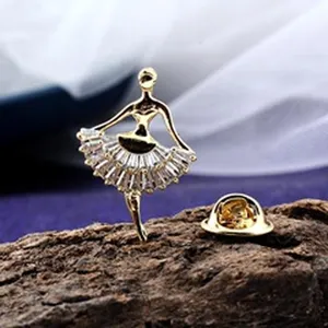Detailansicht einer goldenen Ballerina-Brosche mit funkelndem Kristall-Tutu auf Holz