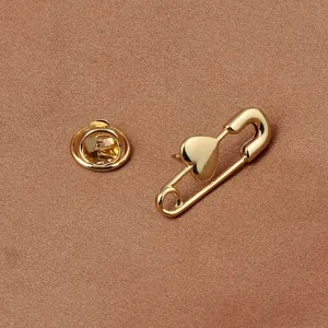 Detailaufnahme einer eleganten goldfarbenen Herz-Sicherheitsnadel auf Satin-Stoff