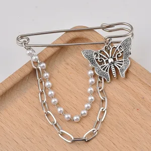 Close-up of vintage silver butterfly brooch with pearl and metal decorative chains