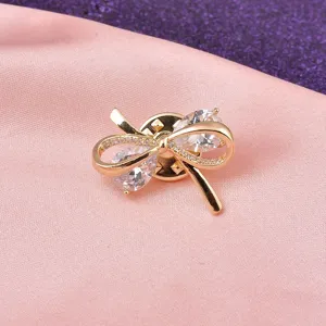 Gedetailleerde macro-opname van een elegante gouden strikbrosche met fonkelende zirkonia.
