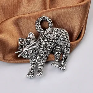 Dettaglio di una spilla a forma di gatto vintage con pietre nere scintillanti e argento.