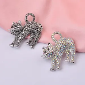 Dettaglio di spille a forma di gatto con strass neri e iridescenti molto eleganti.