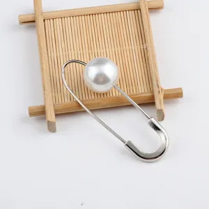 Detailansicht einer handgefertigten Sicherheitsnadel-Brosche mit großer weißer Perle.