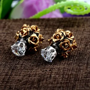 Makroaufnahme von doppelseitigen Ohrringen mit goldenen Rosen und klarem Zirkon.