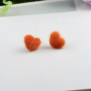 Detailansicht der orangefarbenen flauschigen Herzohrringe aus Nerzfell für Wintermode