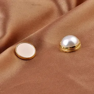Close-up detail of a white pearl magnetic anti-exposure brooch on elegant brown silk fabric