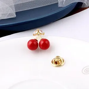 Macro view of a cute cherry-shaped brooch pin with red beads and sparkling crystal leaf