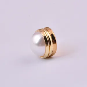 Macro detail of elegant white pearl magnetic brooch with a polished gold metallic base