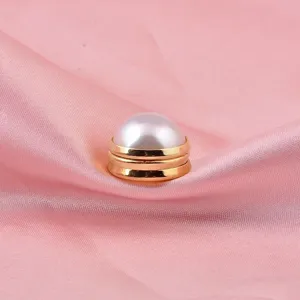 Close-up detail of a premium white pearl magnetic brooch pin displayed on pink satin fabric