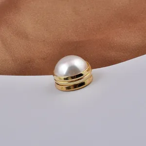 Macro detail of a high-quality pearl magnetic brooch with a sleek golden metal base
