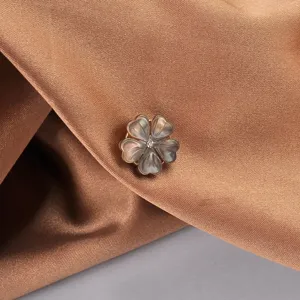 Dettaglio macro di una spilla a fiore in conchiglia naturale su elegante raso marrone
