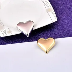 Detail view showing polished heart-shaped metal brooches in gold and silver tones