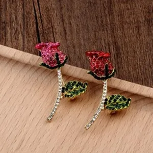 Close-up of elegant rose flower brooches with red and pink crystals on a wooden surface