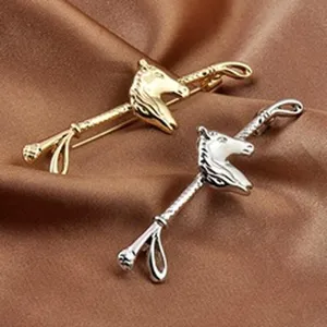 Detailed view of elegant gold and silver horse head brooches on satin fabric