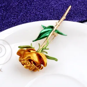 Detaillierte Makroaufnahme einer eleganten goldenen Rosenbrosche mit grünen Blättern und Stiel