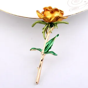 Detailansicht einer eleganten goldenen Rosenbrosche mit grünen Emaille-Blättern