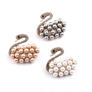 Elegant swan brooches with pearls and rhinestones in grey, champagne, and white colors.