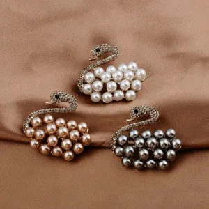 Elegant pearl swan brooches in three colors with sparkling rhinestones on brown silk