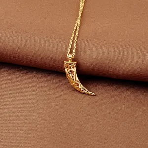 Detailed macro view of an 18K gold plated tooth pendant necklace with filigree